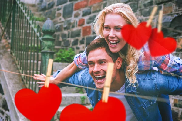 Couple having fun against hearts — Stock Photo, Image