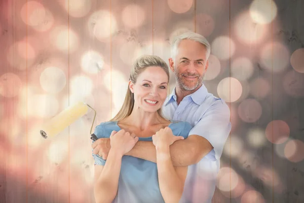 Casal abraçando e segurando rolo de pintura — Fotografia de Stock