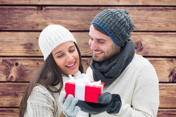 Pareja de invierno sosteniendo regalo contra tablones de madera — Foto de Stock