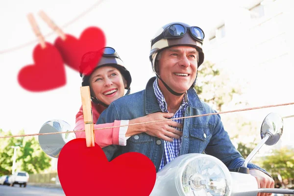 Pareja montando un ciclomotor contra corazones — Foto de Stock