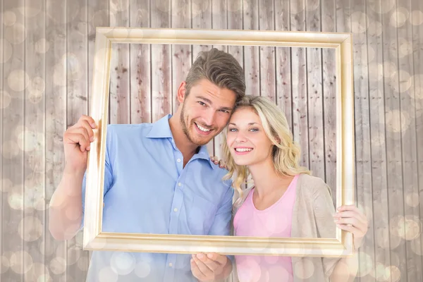 Jovem casal segurando quadro de imagem — Fotografia de Stock