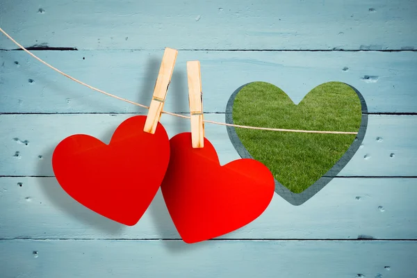 Hearts hanging on line against heart in wood — Stock Photo, Image