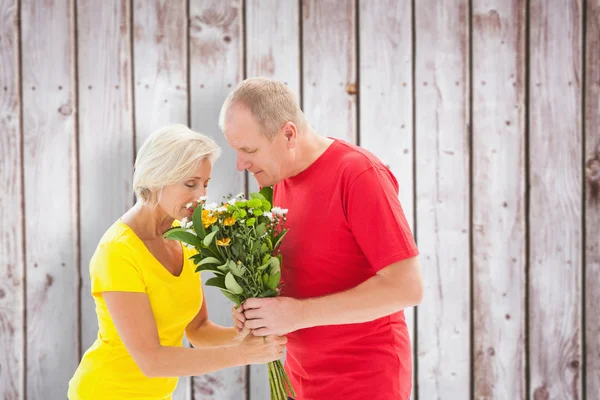 Mature man offering his partner flowers — Stock Photo, Image