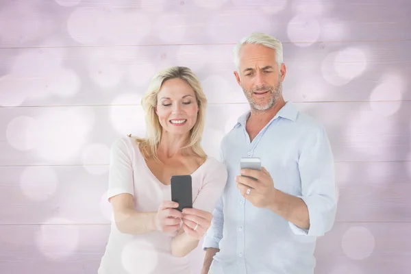 Lyckliga paret textning på deras smartphones — Stockfoto