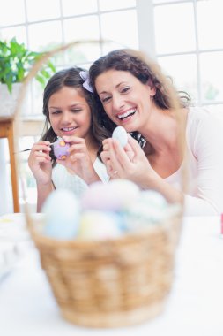 Happy mother and daughter painting easter eggs  clipart