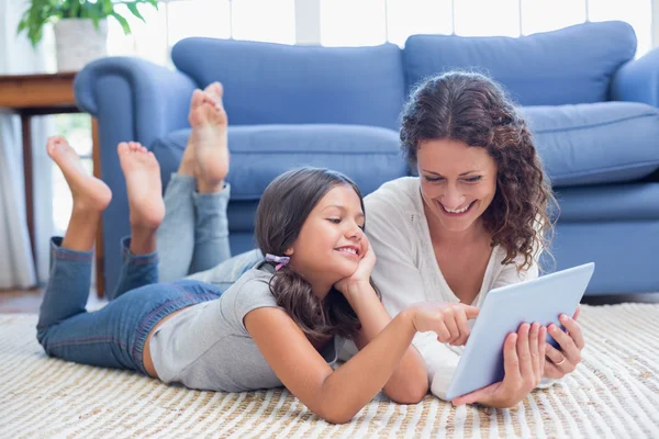 Happy mother and daughter lying on the floor and using tablet — Stock Photo, Image