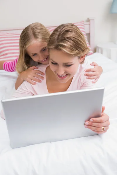 Anne ve kızı kullanarak birlikte yatağa tablet — Stok fotoğraf