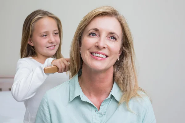 Sevimli kızın anneler saçları fırçalama — Stok fotoğraf