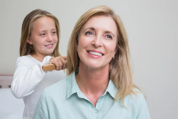 Menina bonito escovar o cabelo de suas mães — Fotografia de Stock