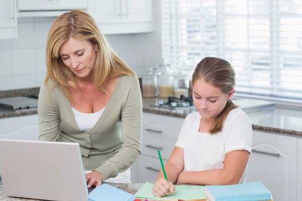 Mère utilisant un ordinateur portable pendant que sa fille fait ses devoirs — Photo