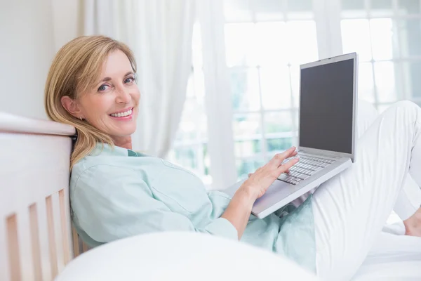 Happy woman using laptop in her bed — Stock Photo, Image