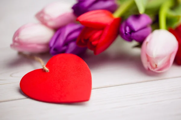 Manojo de tulipanes y tarjeta del corazón — Foto de Stock