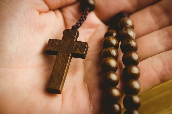 Tangan memegang manik-manik rosario kayu — Stok Foto