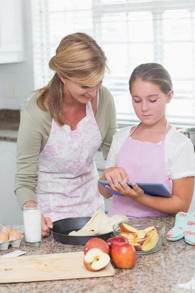 Mutlu anne ve kızı tablet ile birlikte pasta hazırlanıyor — Stok fotoğraf