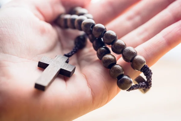 Mano sosteniendo cuentas de rosario de madera — Foto de Stock