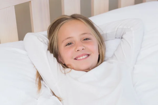 Happy little girl lying in her bed — Stock Photo, Image