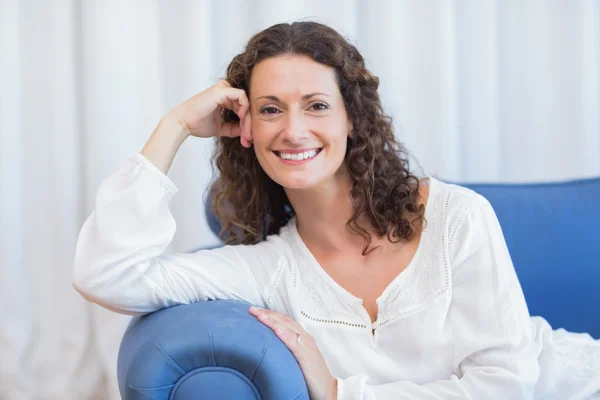 Smiling woman sitting on the couch — Stock Photo, Image