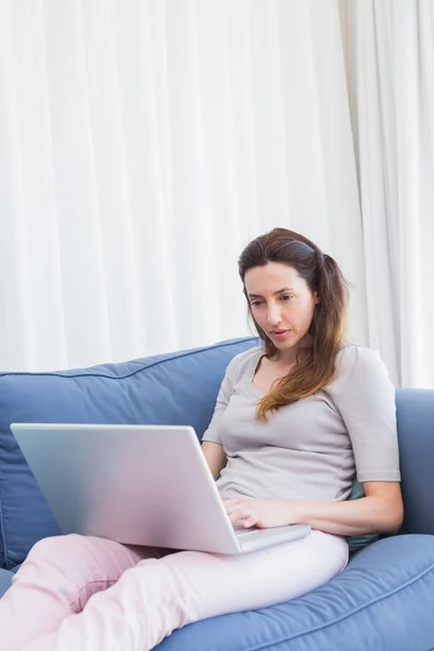 Casual woman using laptop on couch — Stock Photo, Image