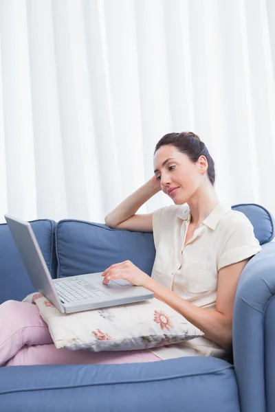 Casual brunette using laptop on couch — Stock Photo, Image