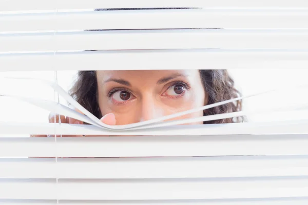Mulher curiosa olhando através de persianas — Fotografia de Stock