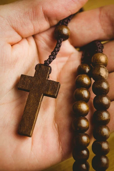 Mano sosteniendo cuentas de rosario de madera — Foto de Stock