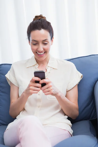 Casual brunette using phone on couch — Stock Photo, Image
