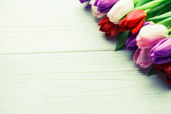 Tulipanes coloridos en mesa de madera — Foto de Stock