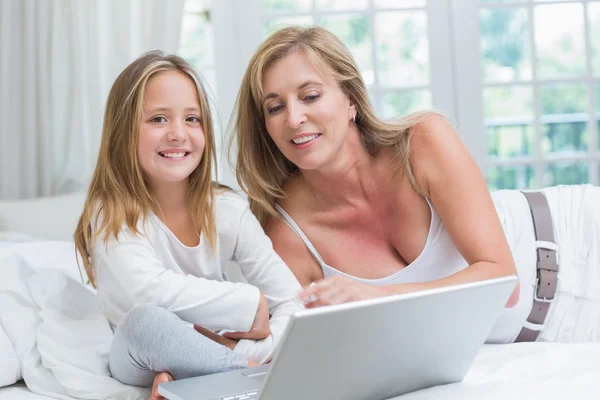 Anne ve kızı yatakta dizüstü bilgisayar kullanarak — Stok fotoğraf
