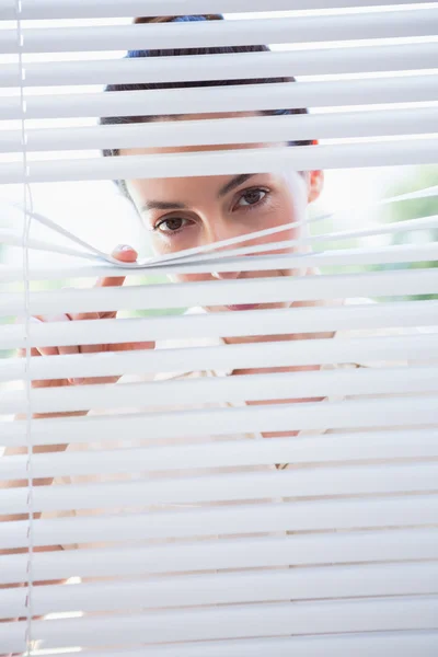Woman peeking through blinds — Stock Photo, Image