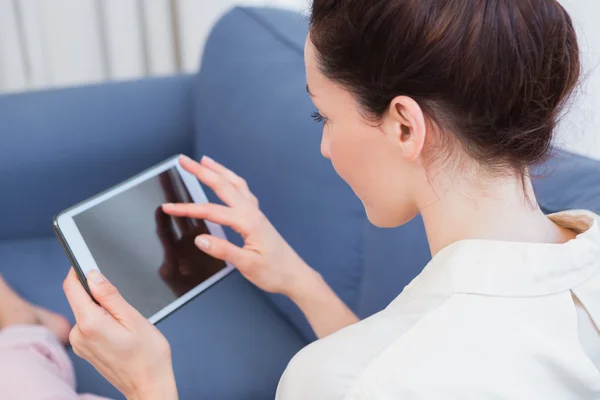 Casual brunette using tablet on couch — Stock Photo, Image
