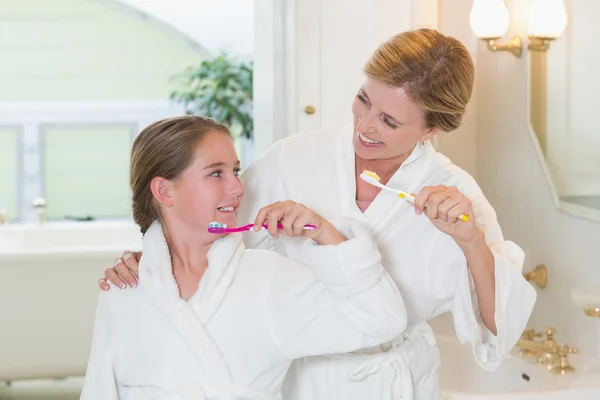 Happy mother and daughter brushing teeth together — Stock Photo, Image