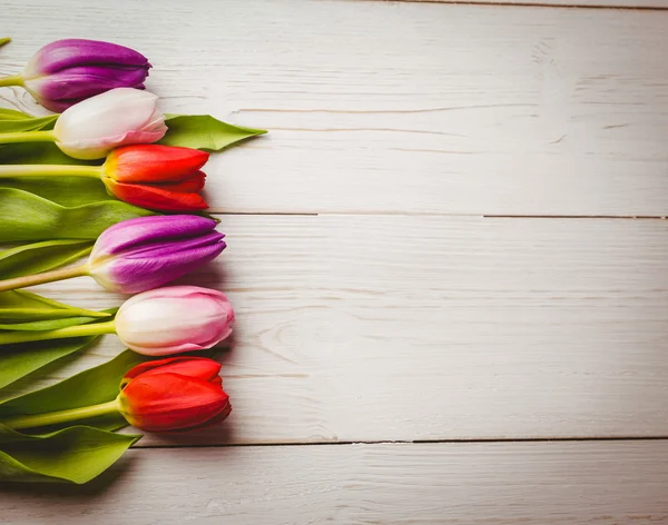 Tulipány na dřevěný stůl — Stock fotografie