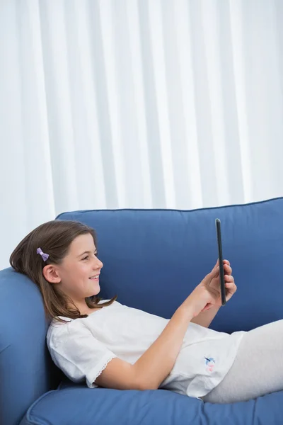 Little girl using digital tablet on the couch — Stock Photo, Image