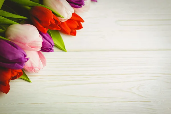 Tulipanes coloridos en mesa de madera — Foto de Stock