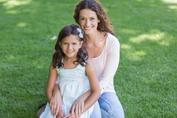 Mère et fille heureuses assises sur l'herbe — Photo