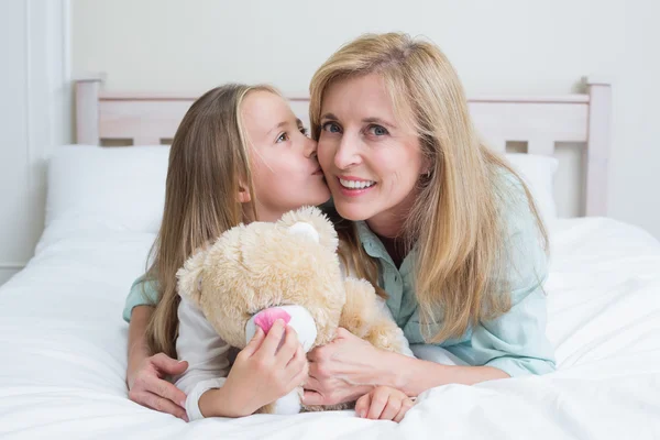 Menina bonito beijando sua mãe sorridente — Fotografia de Stock