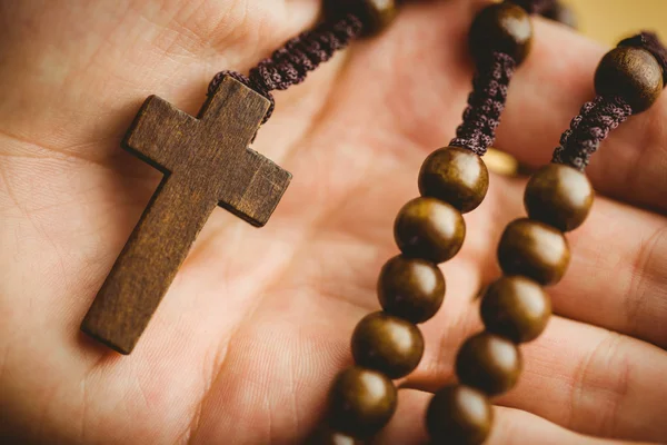 Tangan memegang manik-manik rosario kayu — Stok Foto