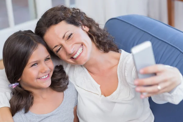 Mãe e filha felizes sentados no sofá e tomando selfie — Fotografia de Stock