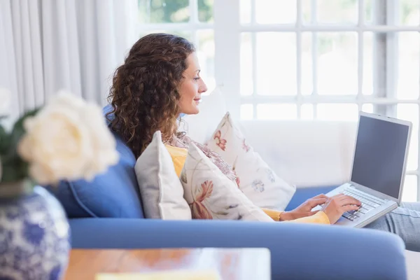 Brünette relaxen auf der couch mit laptop — Stockfoto