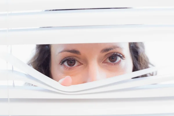 Curious woman looking through blinds — Stock Photo, Image