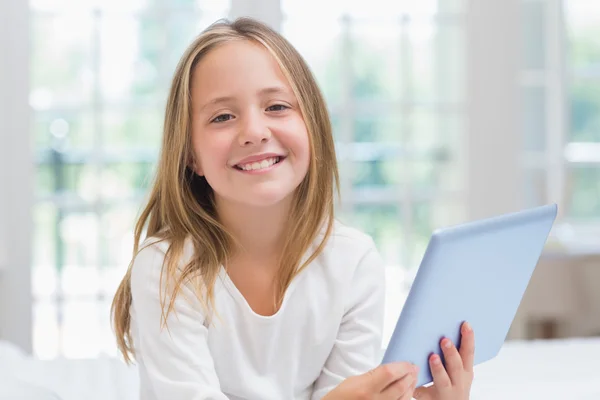 Kleines Mädchen sitzt mit Tablet-PC auf ihrem Bett — Stockfoto