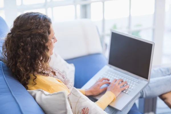Brunette relaxing on the couch with laptop — Stock Photo, Image