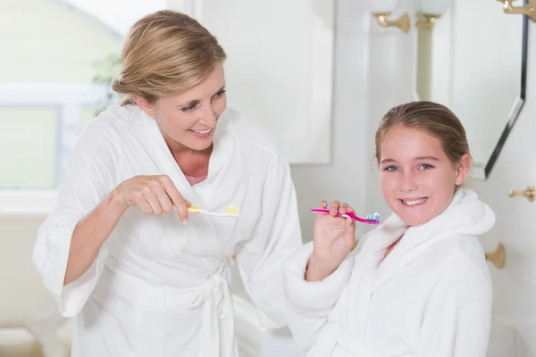 Mãe feliz e filha escovando os dentes juntos — Fotografia de Stock