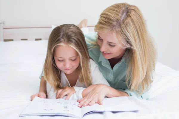 Happy mother and daughter reading a book — Stock Photo, Image