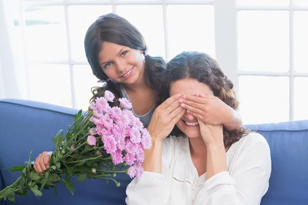 Leende flicka med blommor till sin mamma — Stockfoto