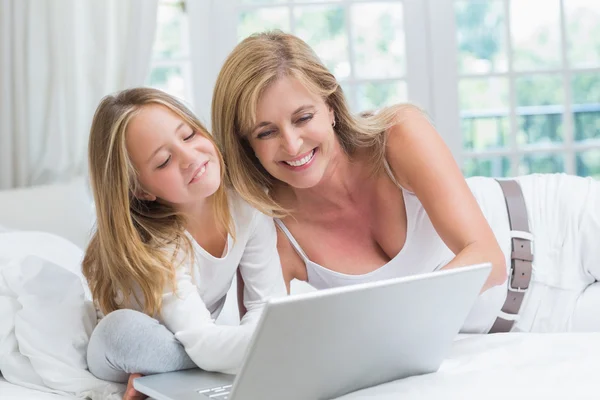 母亲和女儿在床上使用笔记本电脑 — 图库照片