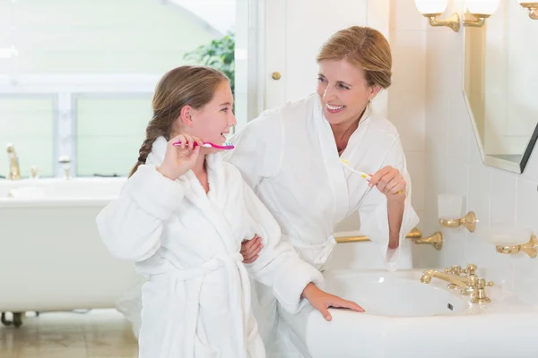 Happy mother and daughter brushing teeth together — Stock Photo, Image