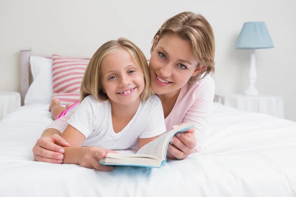 Moeder en dochter leesboek samen op bed — Stockfoto