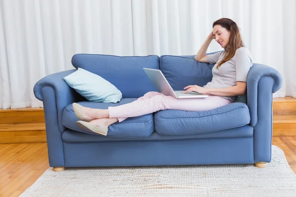 Casual woman using laptop on couch — Stock Photo, Image