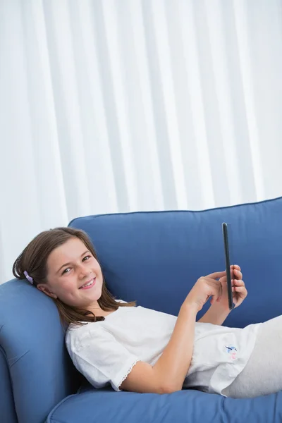 Little girl using digital tablet on the couch — Stock Photo, Image
